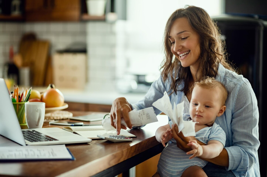 Parent with baby reviewing expenses at home illustrating the cost of having a child.